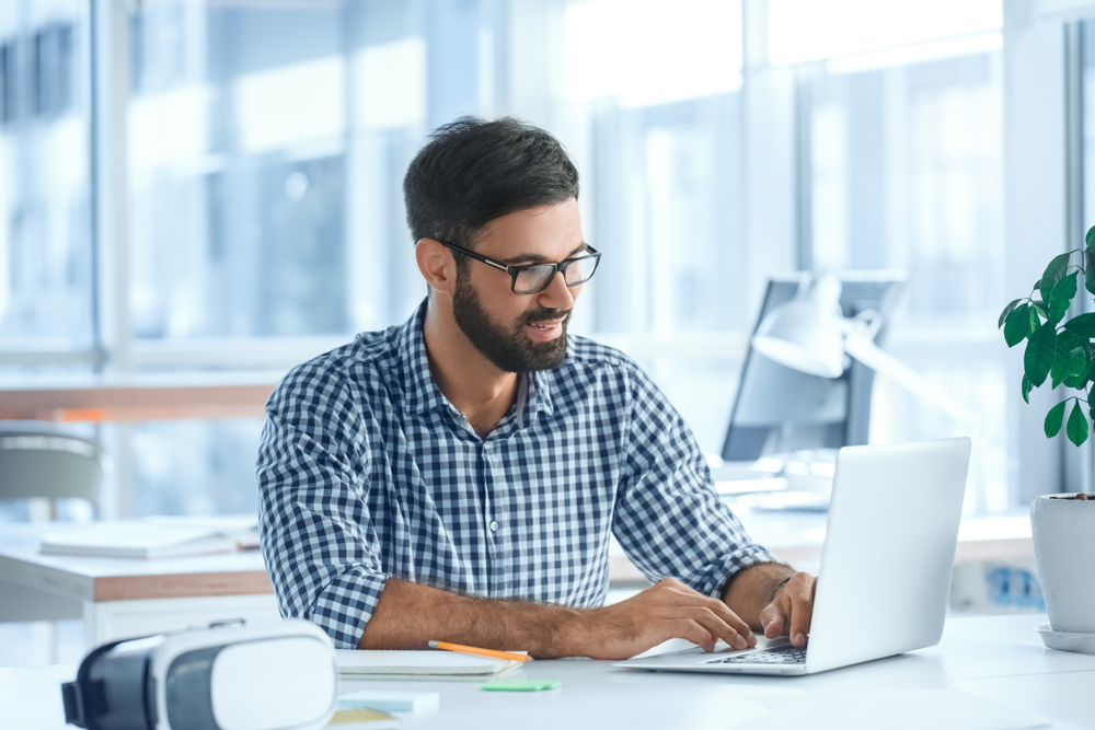 person with glasses working on laptop